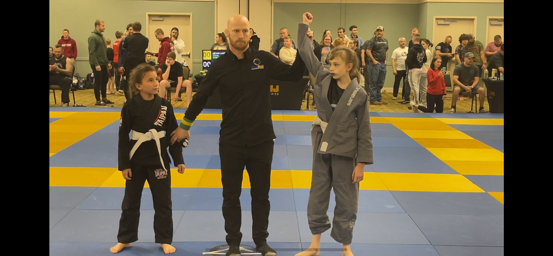 Miley and a competitor with their hands raised after a match